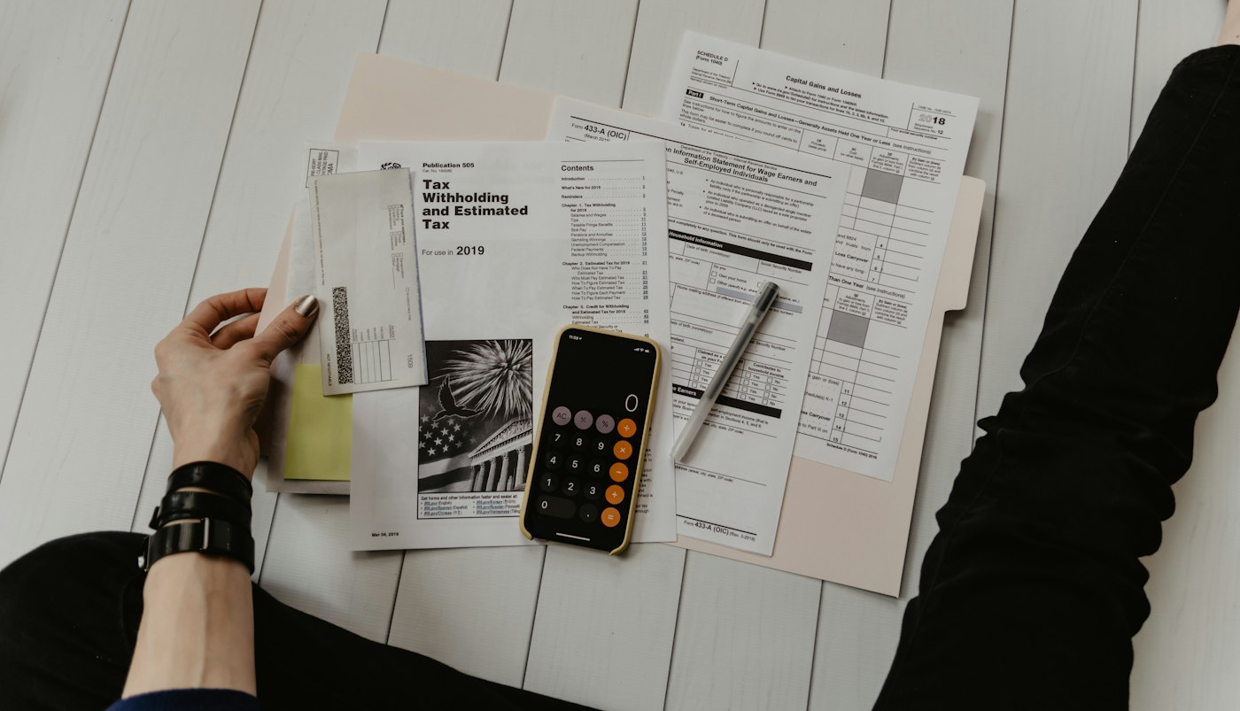 Documentos, formatos fiscales y calculadora sobre un escritorio